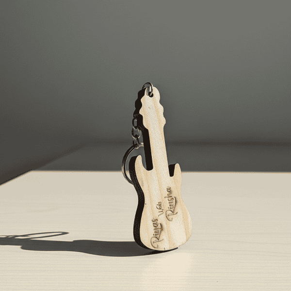 Personalized wooden guitar keyring with engraved text.